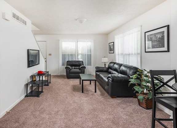 A living room with a black leather couch and a black chair.