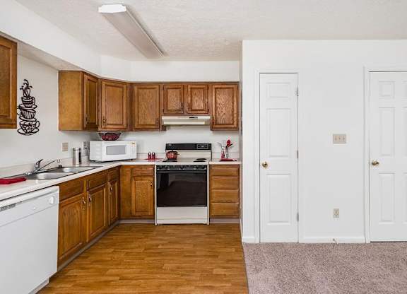 A kitchen with wooden cabinets and white appliances.