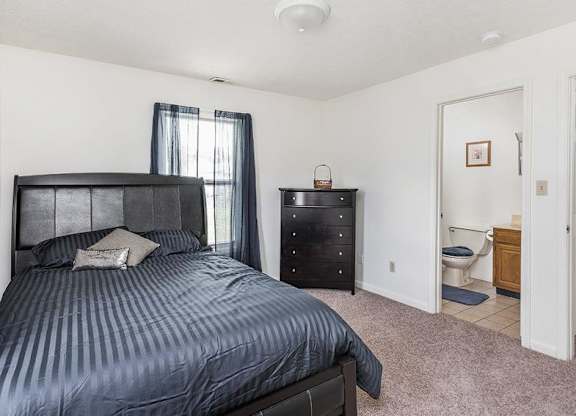 A bedroom with a bed, nightstand, and a small bathroom.