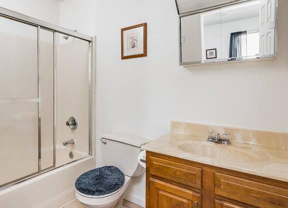 A bathroom with a toilet, sink, and mirror.