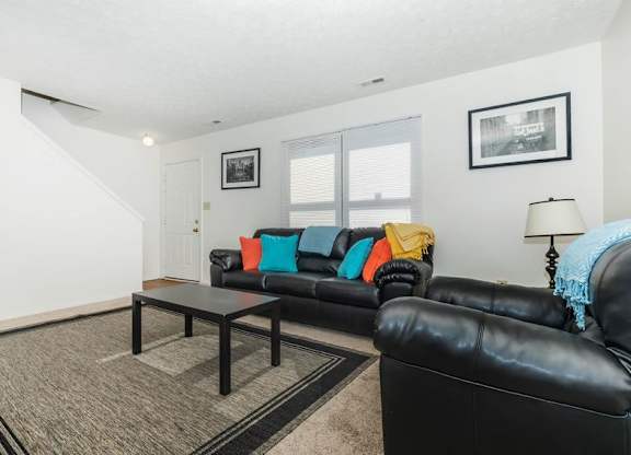 A black leather couch with a black coffee table in front of it.