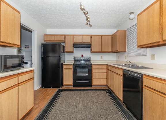A kitchen with wooden cabinets and black appliances.