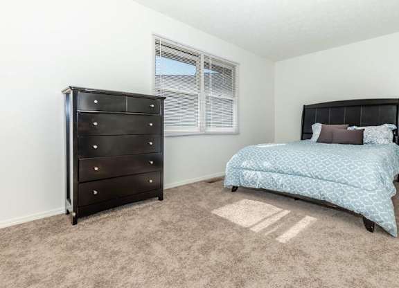 A bedroom with a black dresser and a blue bedspread.