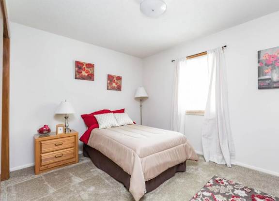 A bedroom with a bed, nightstand, and two pictures on the wall.