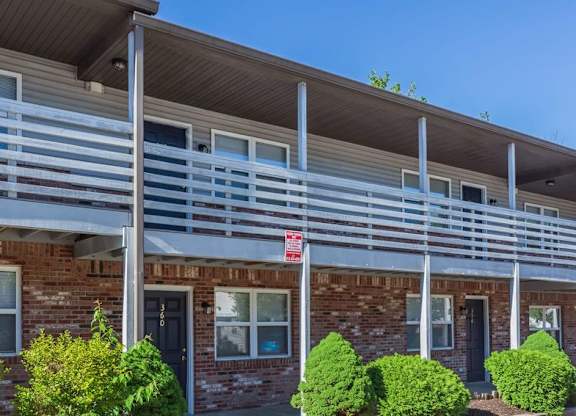 A red and white sign is on the balcony of a brick building.
