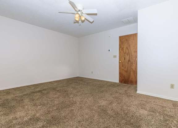 A room with a ceiling fan and carpeted floor.