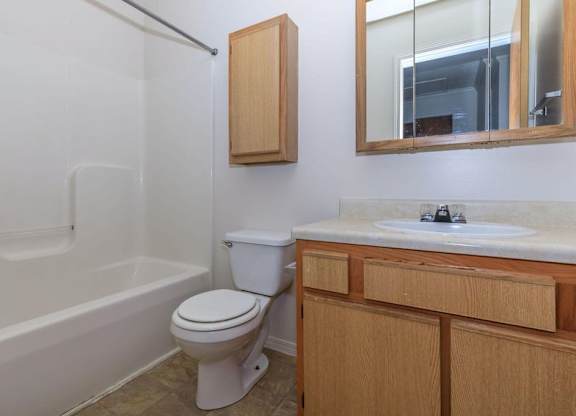 A white toilet sits in a bathroom next to a bathtub and a sink.