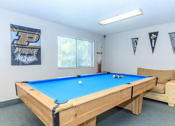 A pool table in a room with Purdue banners on the wall.
