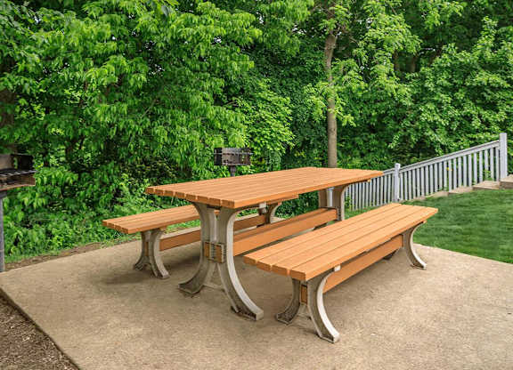 A wooden picnic table with two benches is set on a concrete surface.