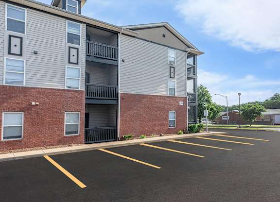 A parking lot in front of a multi-story apartment building.