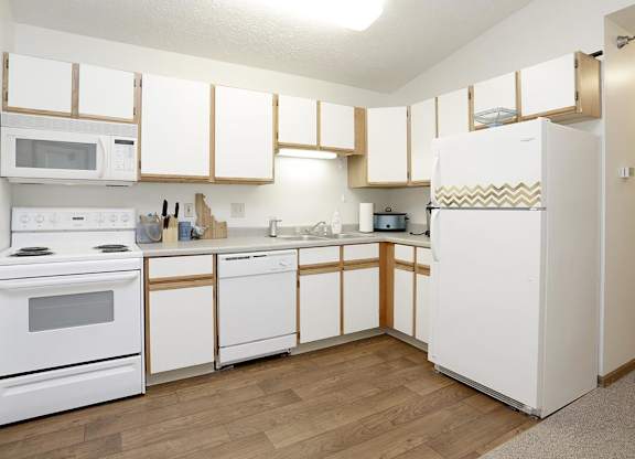 A kitchen with white appliances and wooden cabinets.