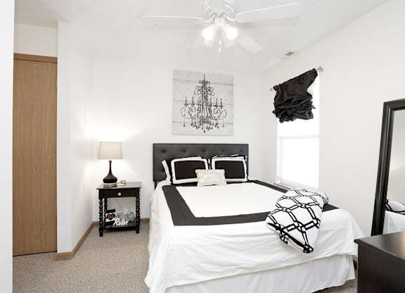 A bedroom with a large bed and a ceiling fan.