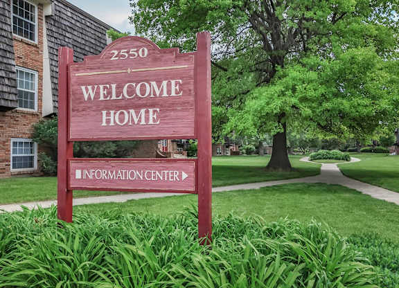 A red sign that says "Welcome Home" in front of a building.