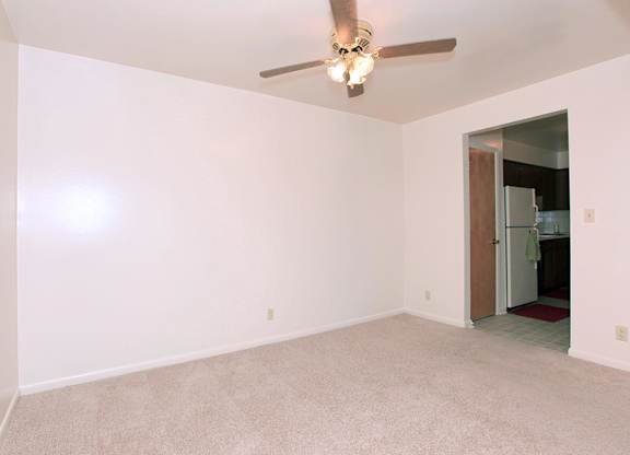 A room with a ceiling fan and carpeted floor.