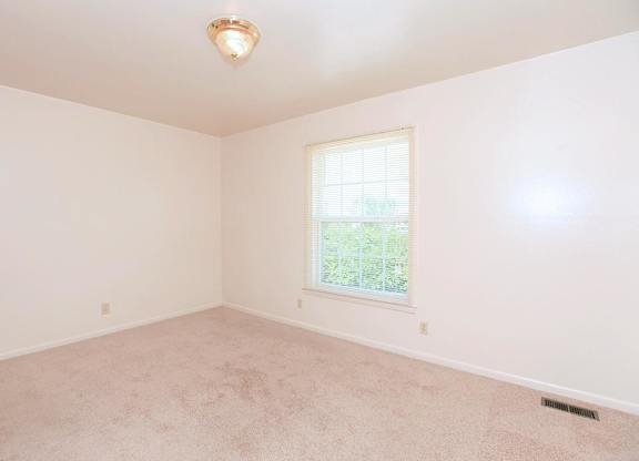 A room with a carpeted floor and a window letting in natural light.