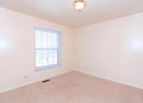 A room with a window and a carpeted floor.