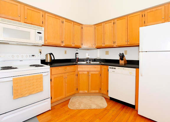A kitchen with white appliances and wooden cabinets.