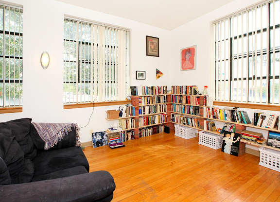 A living room with a black couch and a bookshelf filled with books.