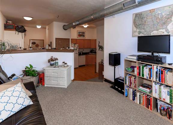 A living room with a couch, bookshelf, and a map on the wall.