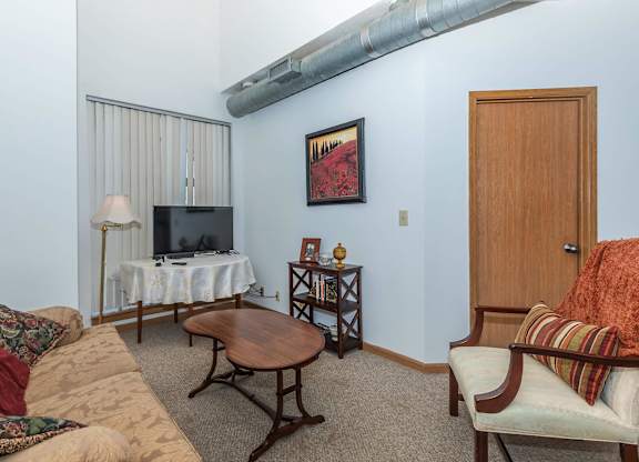 A living room with a couch, a coffee table, a television, and a painting on the wall.