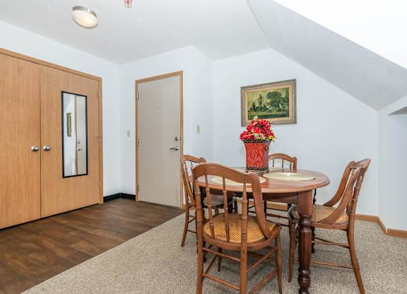 A dining room with a wooden table and chairs.