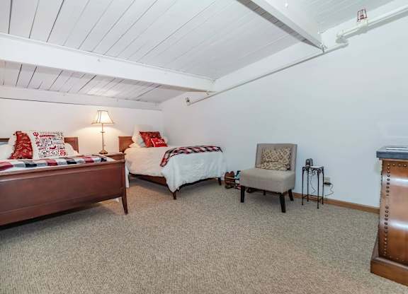 A bedroom with two beds and a chair.