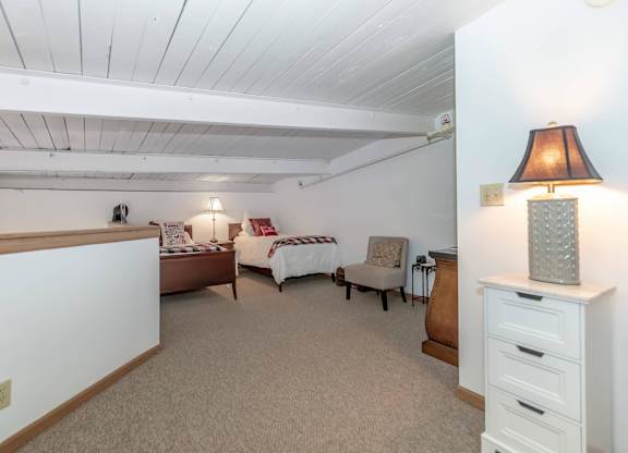 A bedroom with a bed, chair, and lamp.