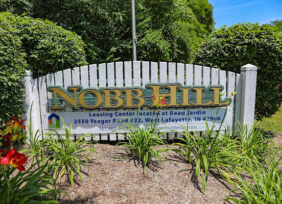 A sign for Nobb Hill Leasing Center is displayed in front of a white fence.