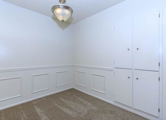 A white room with a carpeted floor and a light fixture on the ceiling.