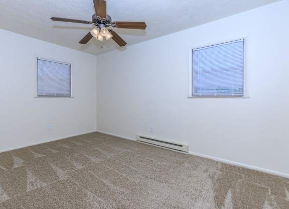 A room with a ceiling fan and carpeted floor.