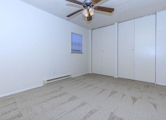 A room with a ceiling fan and carpeted floor.
