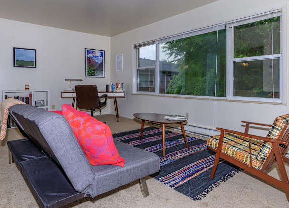 A living room with a grey couch and a wooden chair.