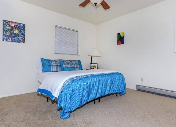 A bedroom with a bed covered in a blue bedspread.