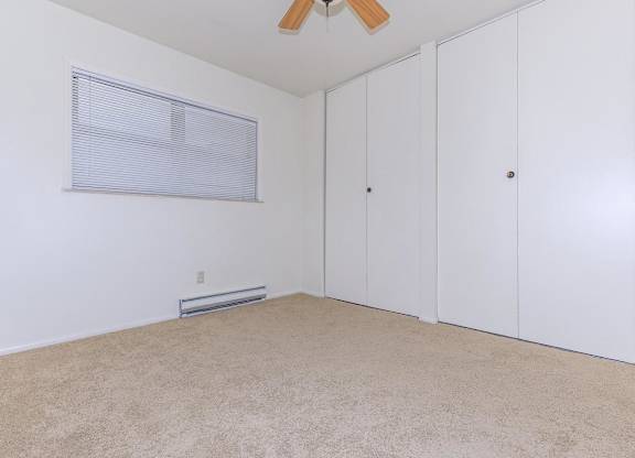 A room with a ceiling fan and three white doors.