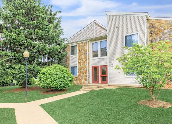 A building with a red door and a tree in front of it.