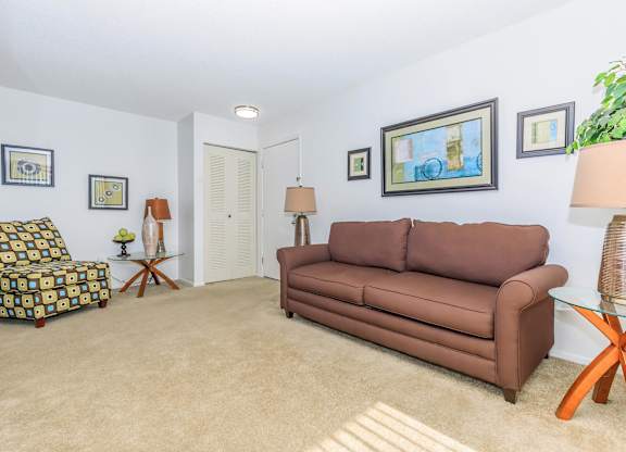 A living room with a brown couch, a patterned chair, and a glass coffee table.