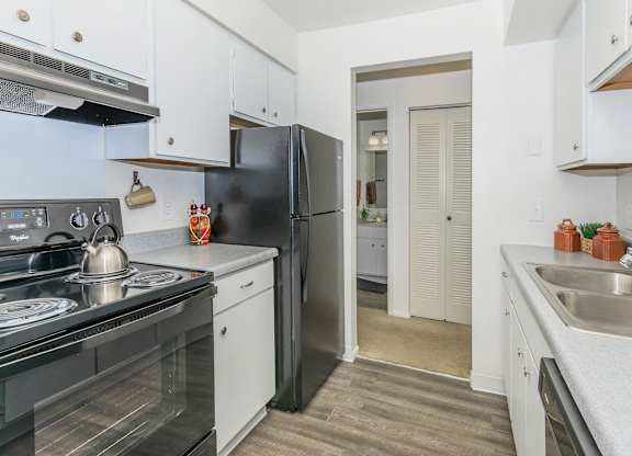 A kitchen with black appliances and white cabinets.