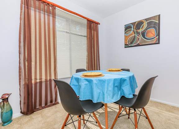 A dining table with a blue tablecloth and two chairs.