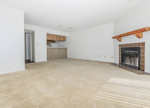 A large, empty room with a fireplace and a doorway leading to another room.