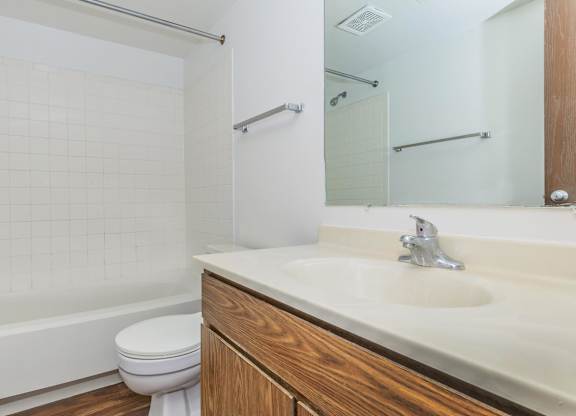 A white tiled bathroom with a toilet, sink, and bathtub.