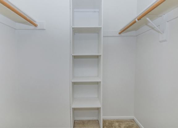 A white shelving unit with four shelves is mounted on a white wall.