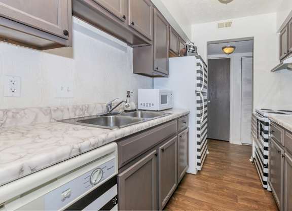 A kitchen with a white fridge and a white sink.