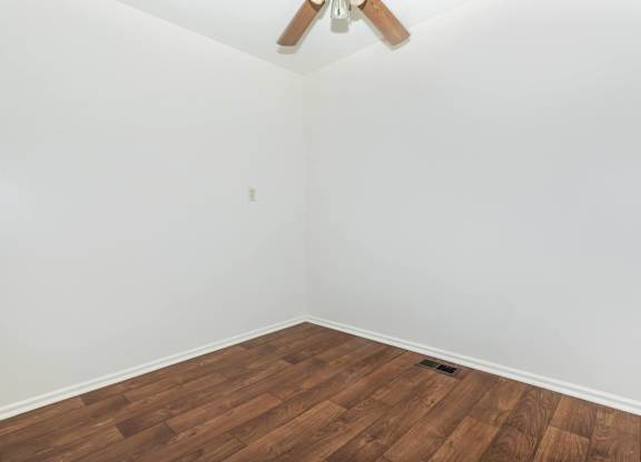 A room with a ceiling fan and wooden flooring.