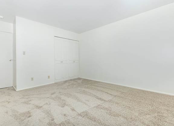 A room with a carpeted floor and two doors.