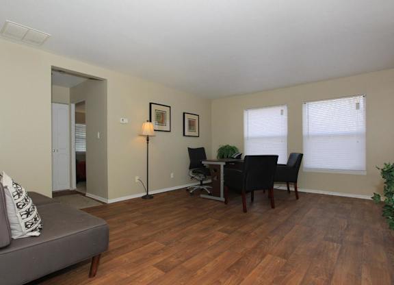 A living room with a grey couch, a dining table with chairs, and a lamp.
