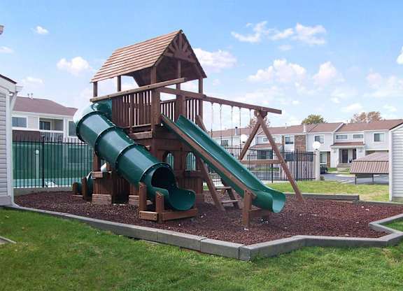 A playground with a green slide and a wooden structure.