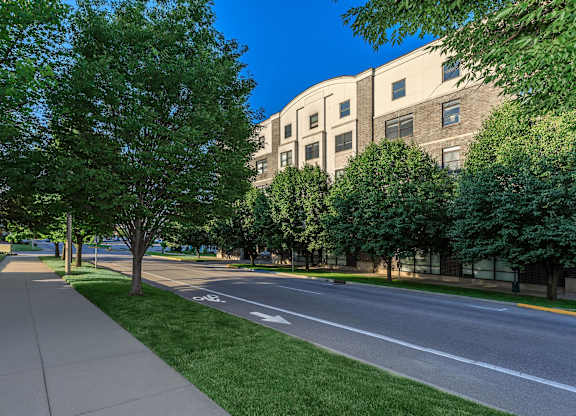 A tree-lined sidewalk runs parallel to a street.