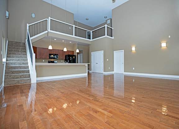 A spacious living room with hardwood floors and a staircase leading to the upper level.