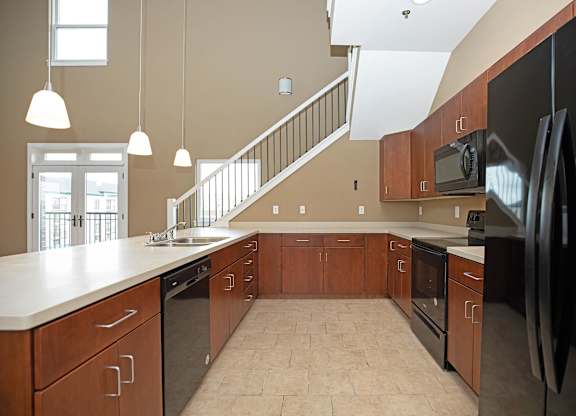 A kitchen with a black refrigerator and wooden cabinets.