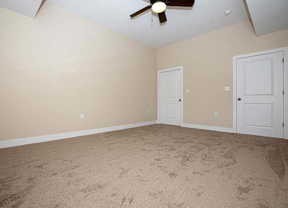 A room with a ceiling fan and two doors.